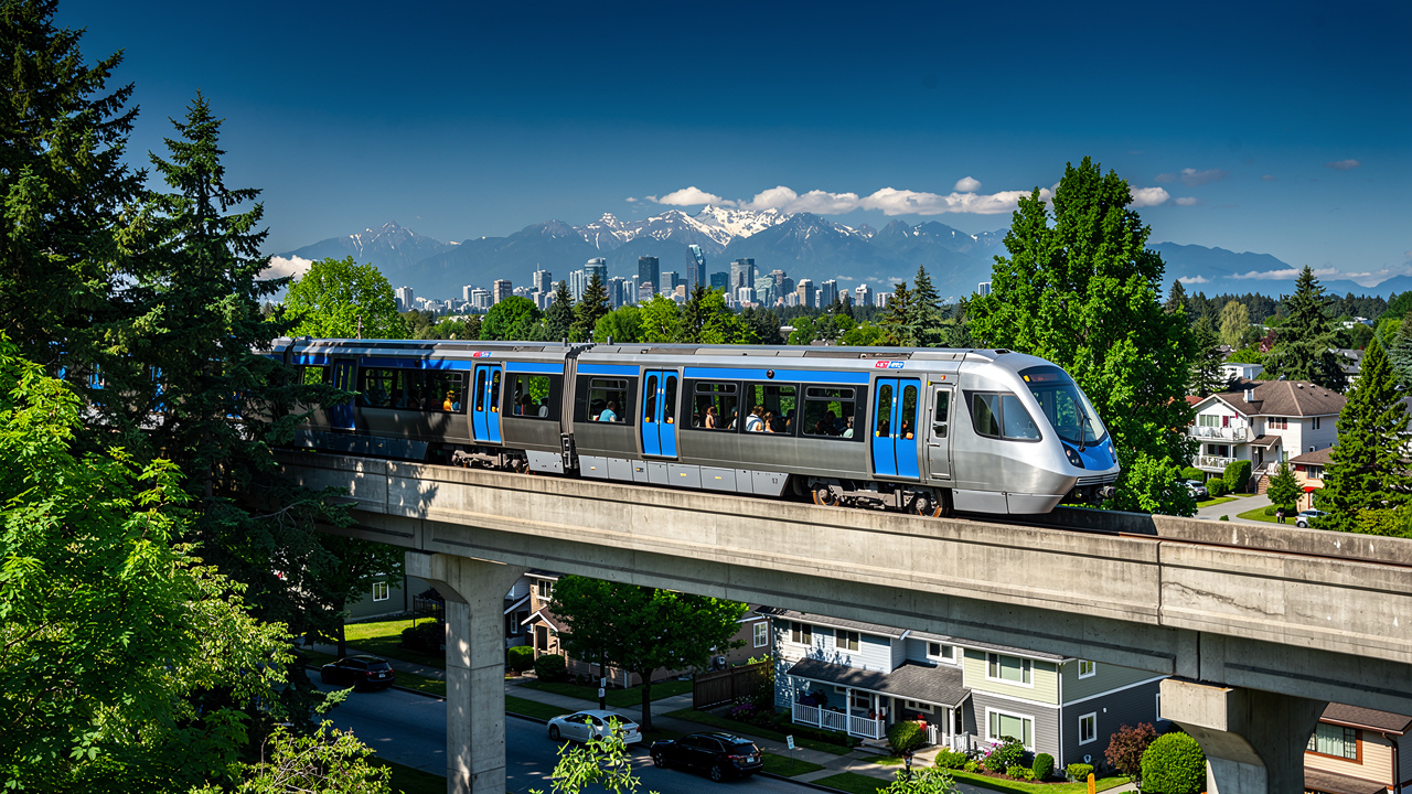 SkyTrain gliding toward Vancouver with mountain backdrop
